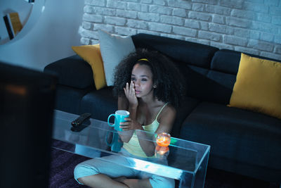 Young woman using mobile phone while sitting on sofa