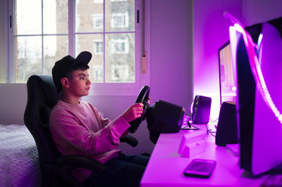 Boy playing video game on computer in bedroom at home