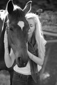 Young woman with eyes closed holding horse head