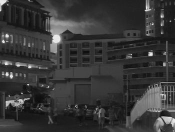 People on illuminated street amidst buildings in city at night