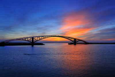 View of bridge over river at sunset