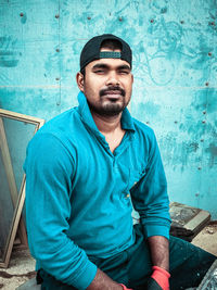 Portrait of young man standing against wall