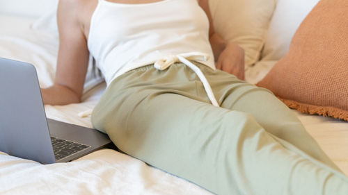 Low section of woman relaxing on bed at home