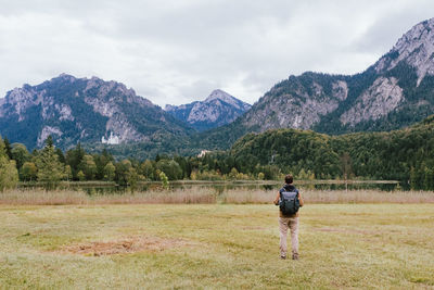 Rear view of man standing on mountain against sky