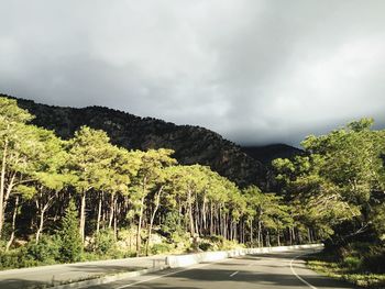Road passing through mountains against cloudy sky