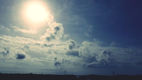 Low angle view of sun shining through clouds