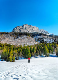 Rear view of person on snowcapped mountain against clear blue sky