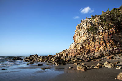 Rocks on beach against blue sky