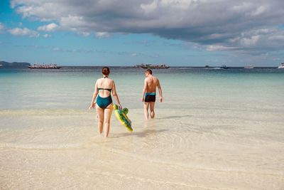 Rear view of men on beach against sky