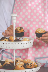 Midsection of chef arranging muffins on cakestand