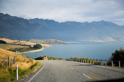 Road by mountains against sky