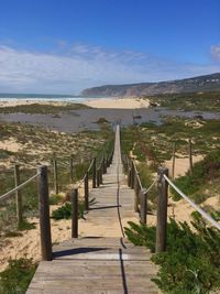 Boardwalk leading towards sea against sky