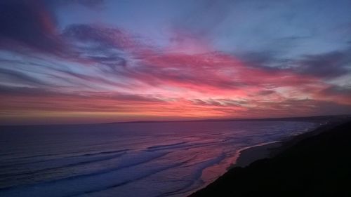 Scenic view of sea against dramatic sky during sunset