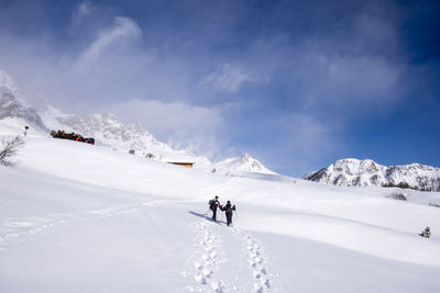 People skiing on snowcapped mountain against sky