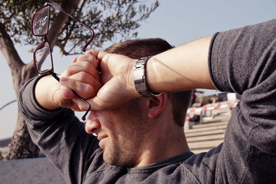 Close-up of young man covering eyes with hands