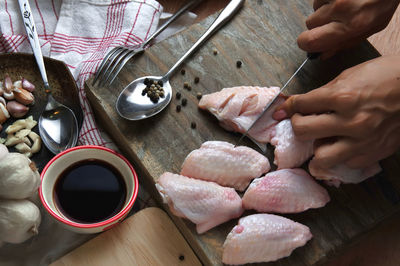 Cropped hands on person cutting meat on cutting board