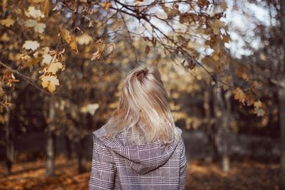 Rear view of woman standing by tree during autumn