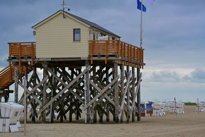 Built structure on beach by sea against sky