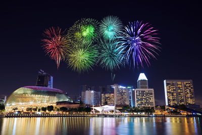 Firework display in city against sky at night