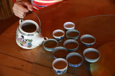 High angle view of hand holding tea cup on table