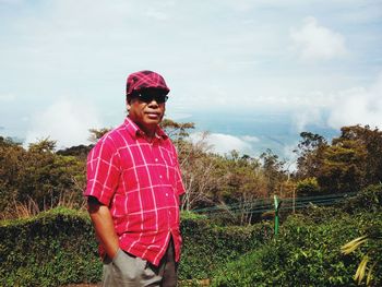 Smiling man standing against trees and sky