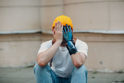 Man holding umbrella standing against wall