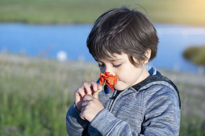 Boy smelling flower while standing outdoors