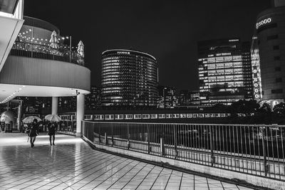 Illuminated modern buildings in city against sky at night