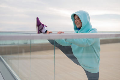 Low angle view of young woman standing by railing