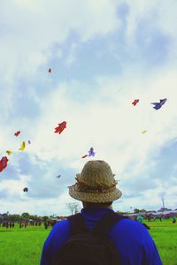 Rear view of woman flying balloons against sky