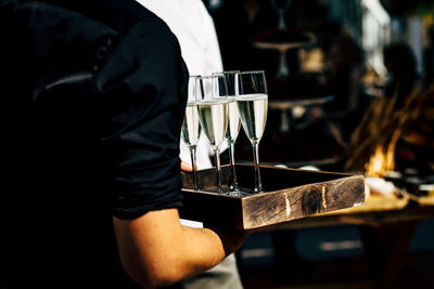 Rear view of waiter holding wine glass at restaurant