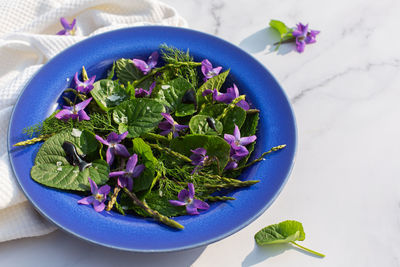 Fresh, delicious spring leaves, lettuce, wild violet flowers and asparagus sprouts salad, raw food