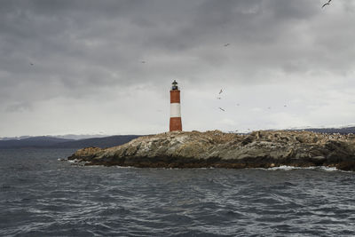 Lighthouse by sea against sky