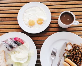 Breakfast of eggs with sausages and noodles on table