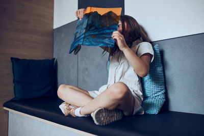 Young woman sitting on sofa at home