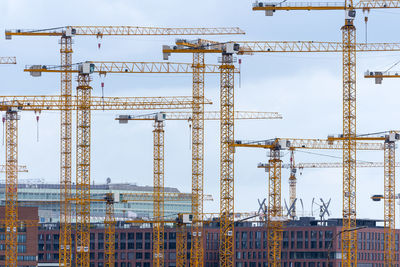 Low angle view of cranes against sky