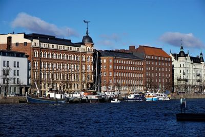 Sailboats in sea against buildings in city