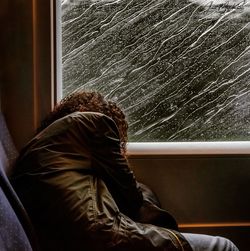 Rear view of woman sitting by window