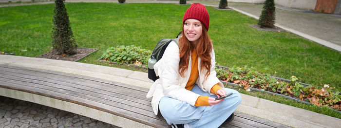 Portrait of smiling young woman sitting on footpath