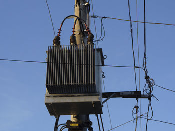 Low angle view of electricity pylon against clear blue sky