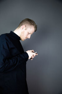 Young man using smart phone against gray background