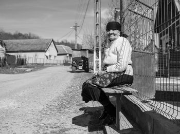 Man sitting on bench against building