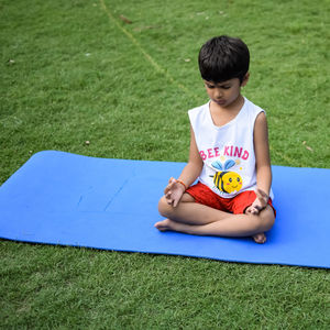 Asian smart kid doing yoga pose in the society park outdoor, children's yoga pose. the little boy