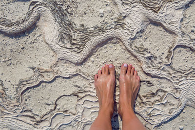 Women feet stand on a white stone surface in pamukkale