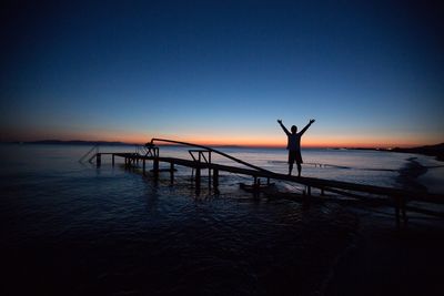 Silhouette man standing on beach against clear sky