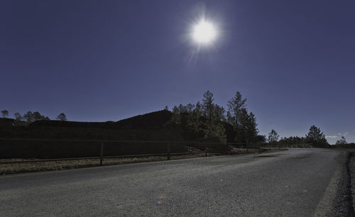 Road by trees against clear sky