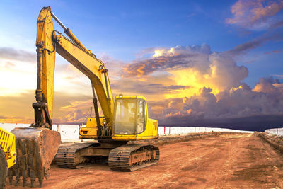 Crane at construction site against sky during sunset