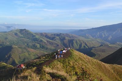 People riding bicycle on mountain against sky