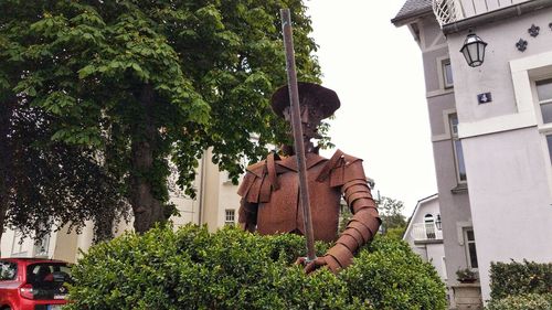 Statue amidst trees and plants against building