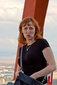 Portrait of woman standing against sky in city